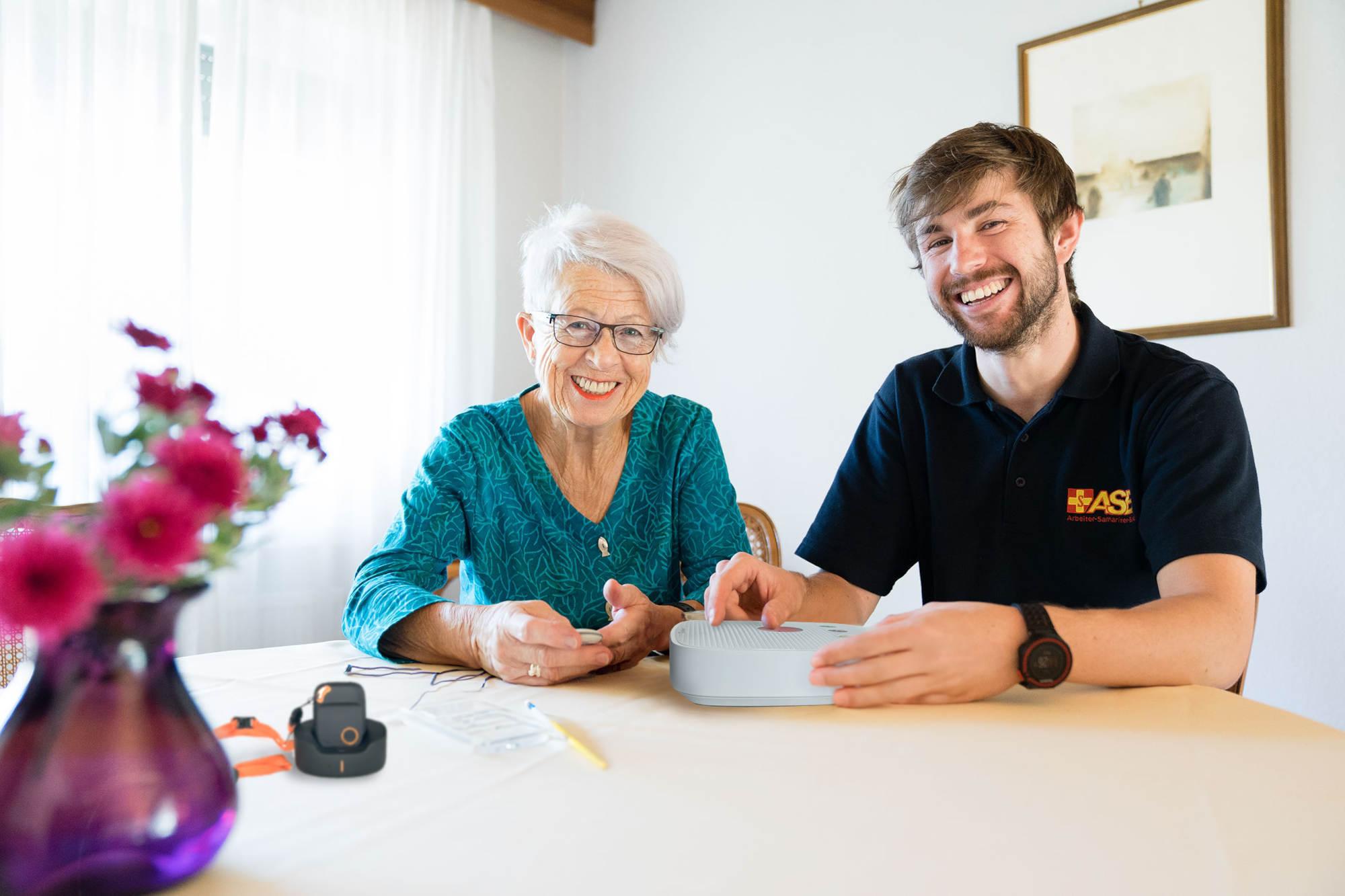 ASB Hausnotruf: Dame mit ASB-Mitarbeiter und Geräten